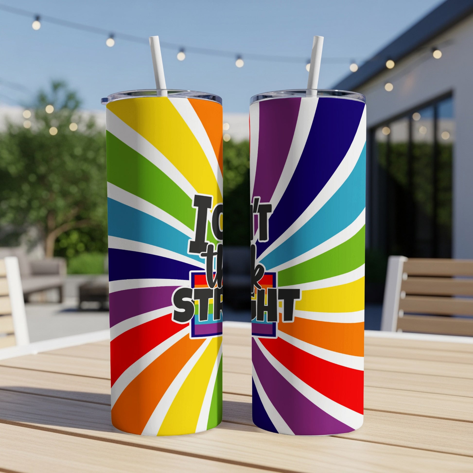 Rainbow striped tumblers with "I'm not straight" text on a patio table.