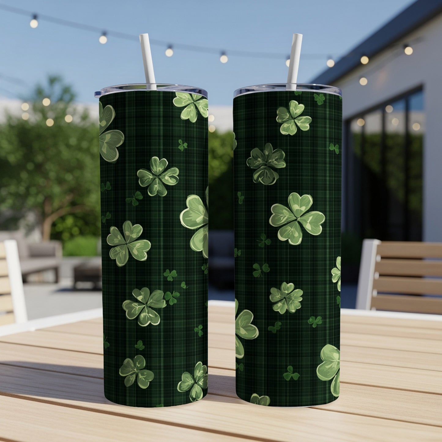 Two green plaid tumblers with shamrock patterns and straws on a table.