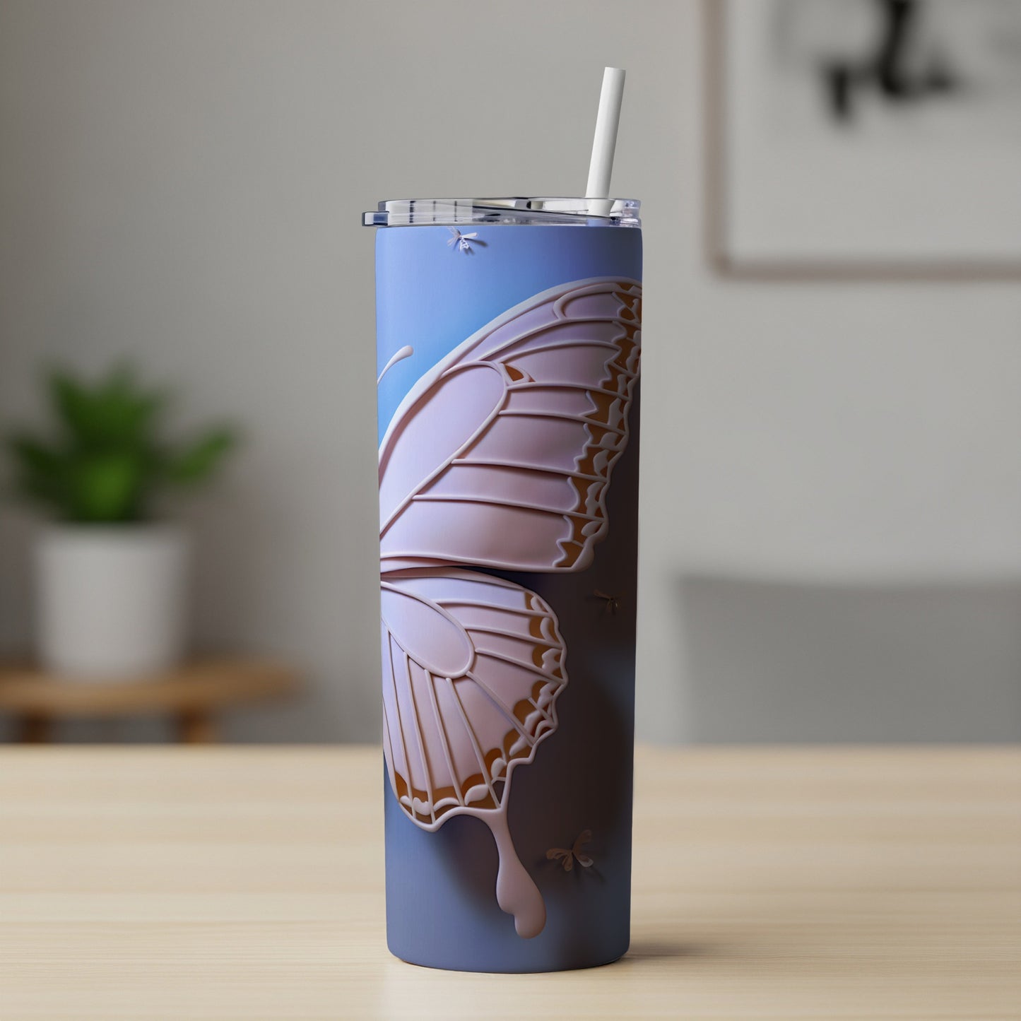 Blue tumbler with a large embossed butterfly wing design and straw.