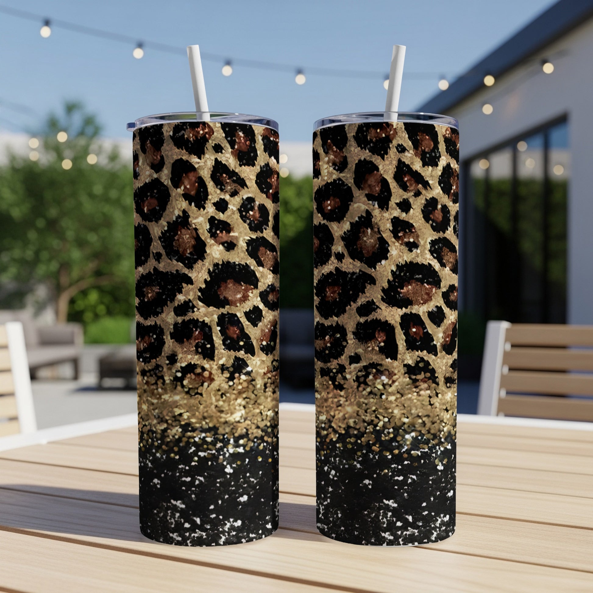 Two tall tumblers with leopard print and glitter detail, standing on a table.