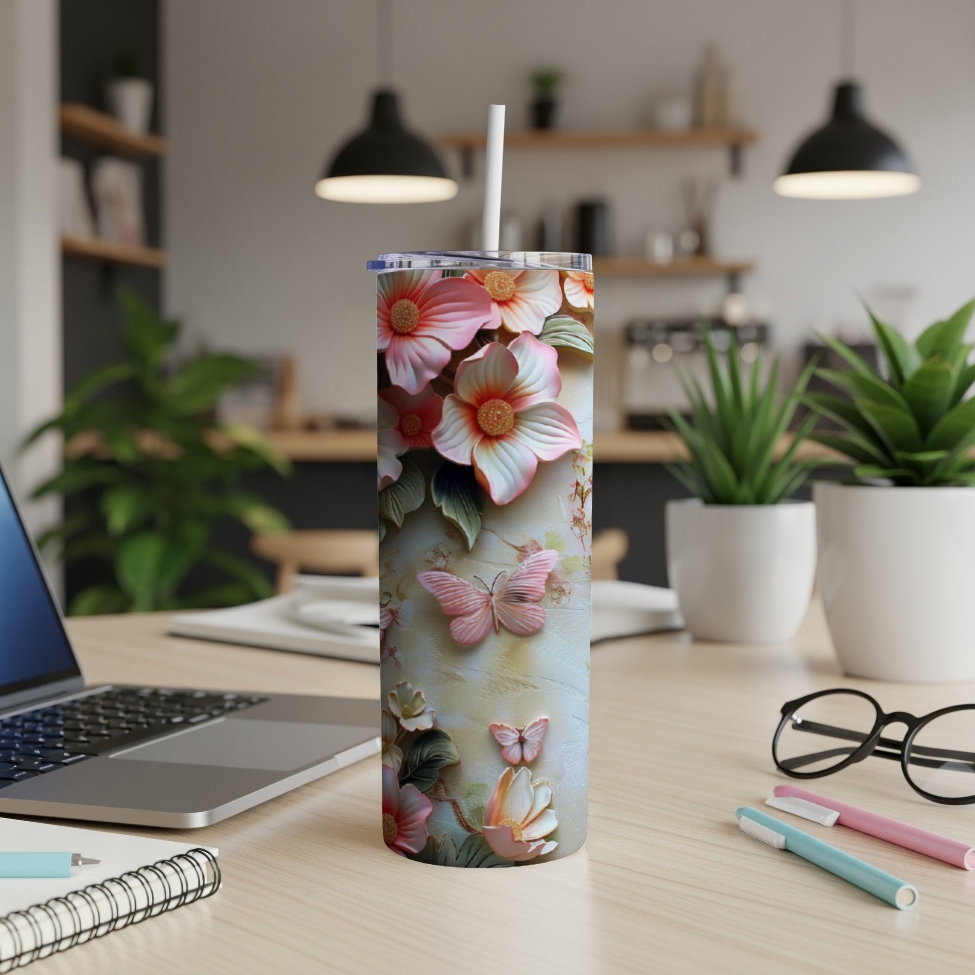 Floral tumbler with butterflies and straw on a desk.