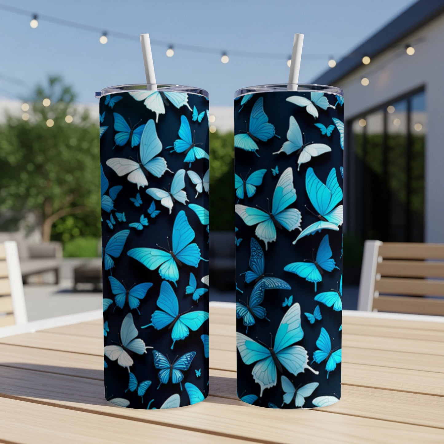 Two tall tumblers with a blue butterfly pattern on a table outdoors.
