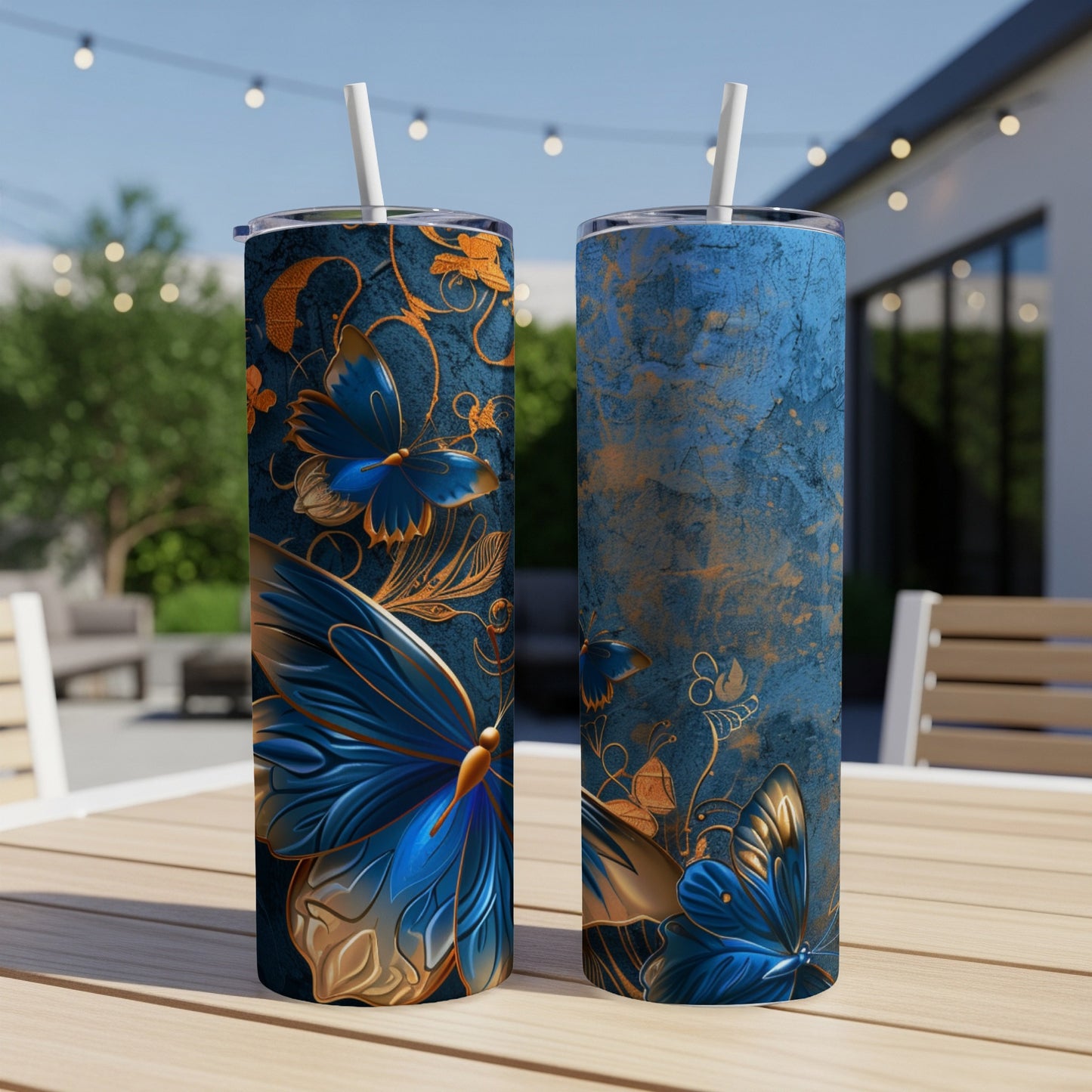 Two blue and gold butterfly tumblers on a wooden table with a backyard scene.