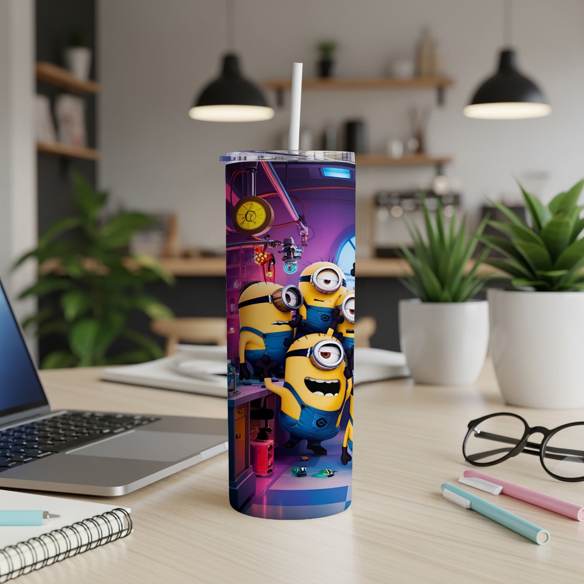 Minions on a tumbler with a straw, sitting on a desk with a laptop.