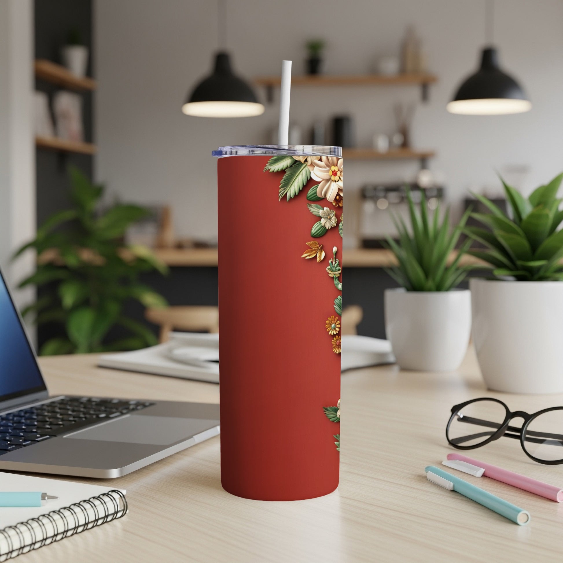 Red tumbler with floral design and white straw on desk.