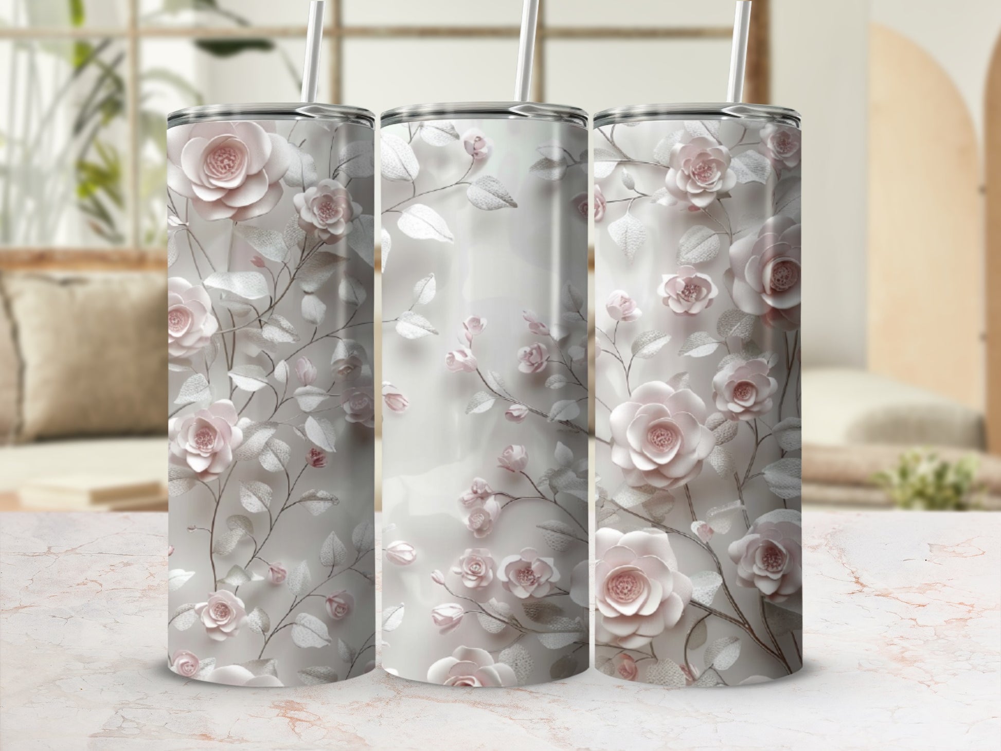 Three tumblers with a pink floral and vine design on a marbled surface.