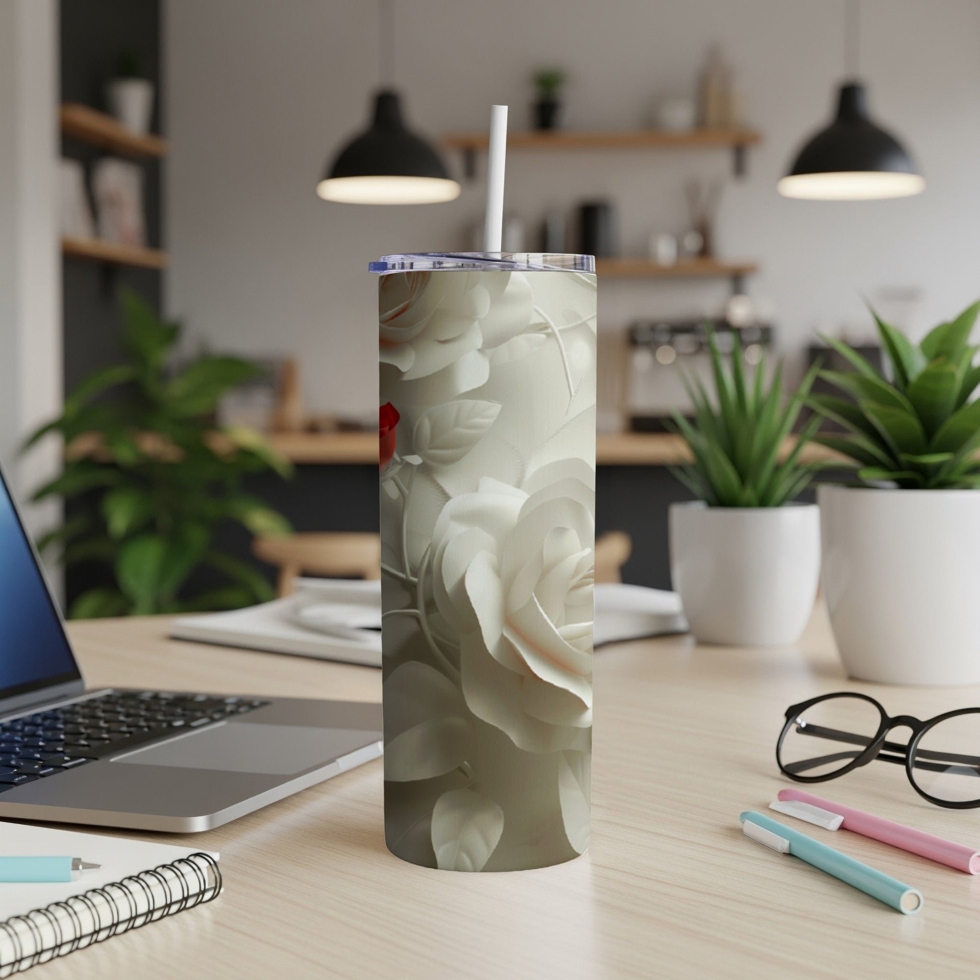 White rose pattern tumbler with a white straw on a wooden desk.