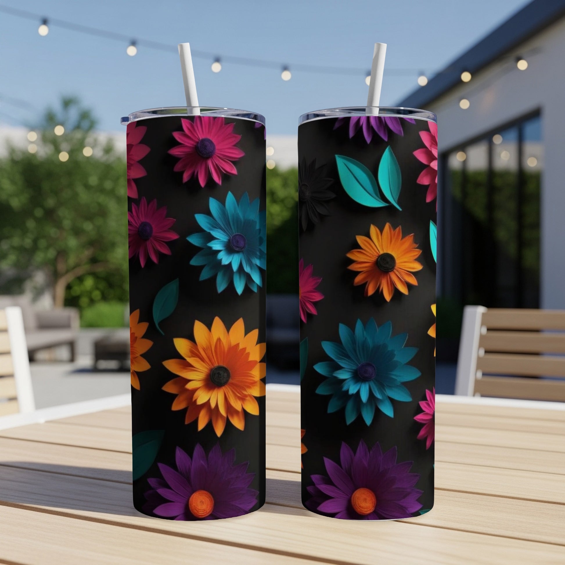Two black tumblers with colorful floral designs displayed outdoors.