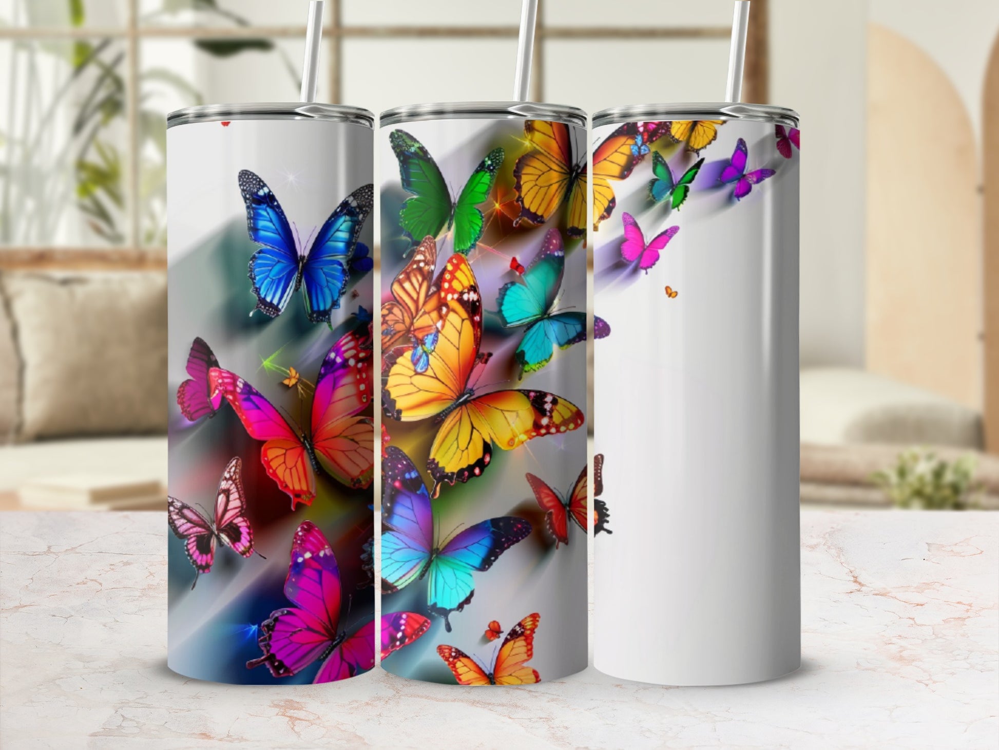 Three tumblers adorned with colorful, vibrant butterflies on a white background.