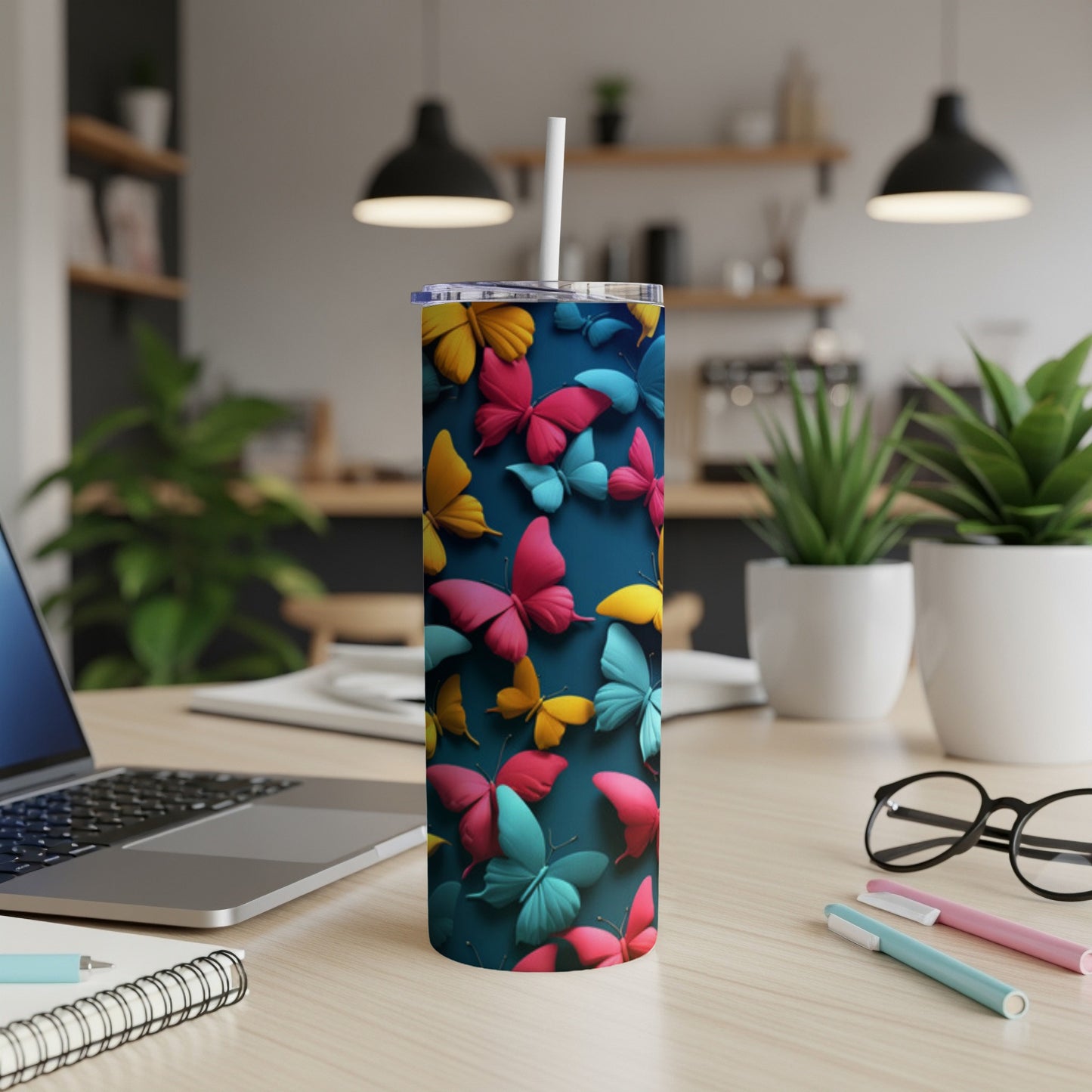 Blue tumbler with colorful butterflies, straw, and office desk background.