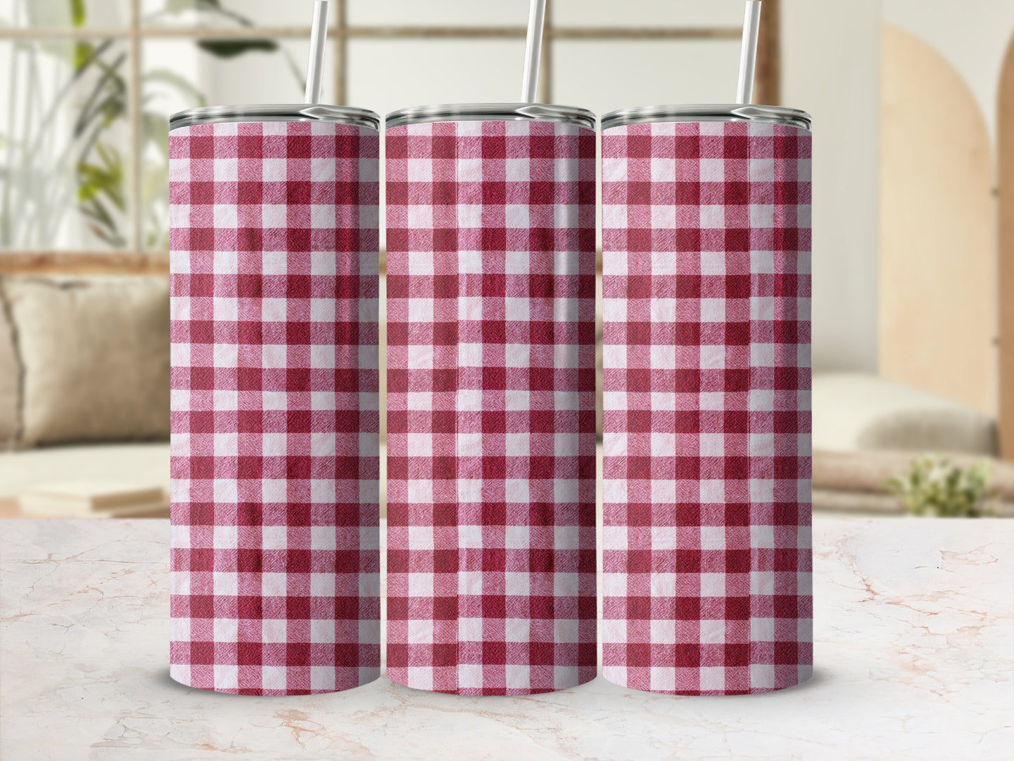 Three red and white checkered tumblers with straws on a marble surface.