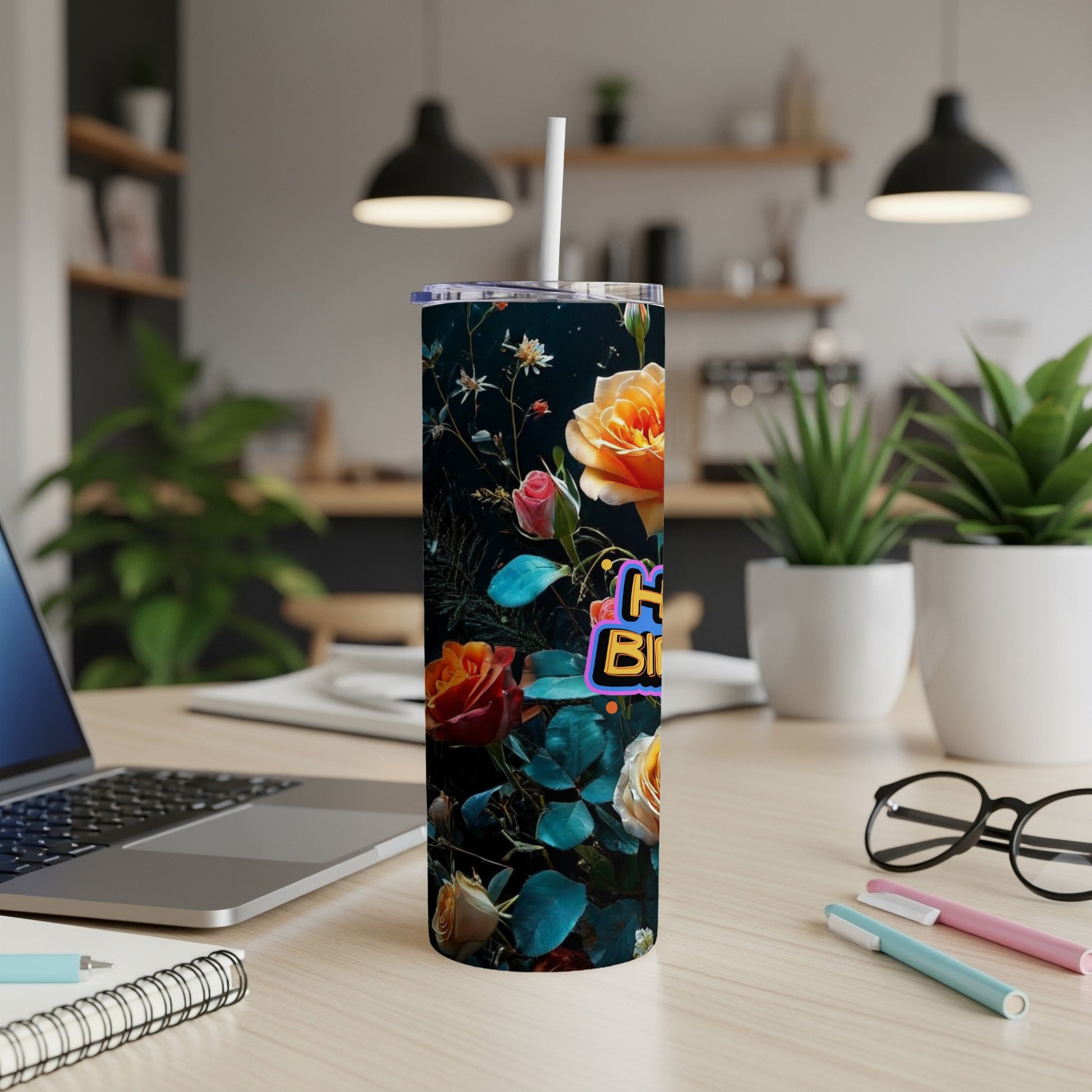 Floral tumbler with "Happy Birthday" text, on a desk.