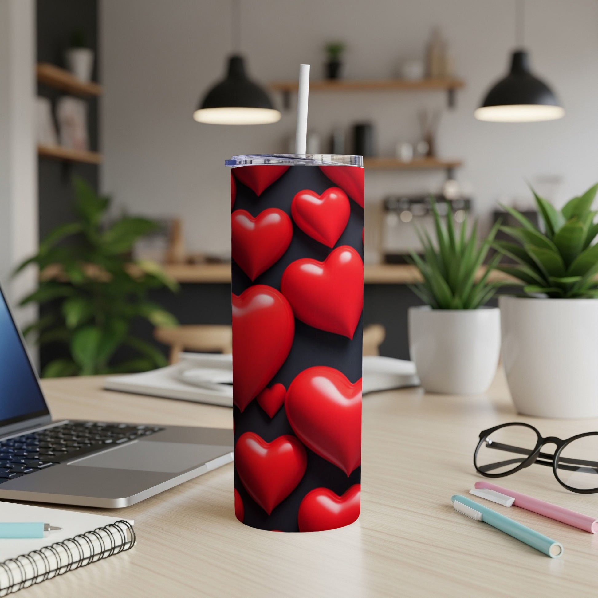 Red hearts pattern on black tumbler with straw on desk.