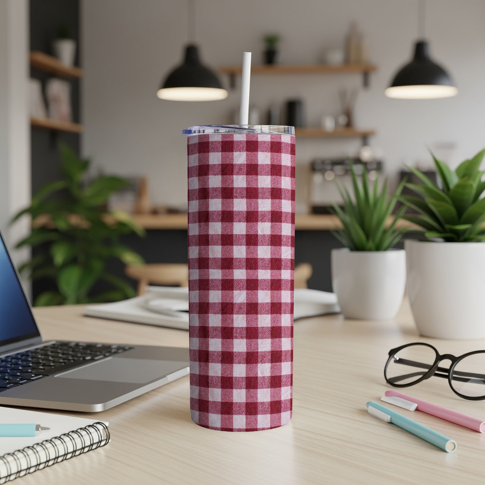 Red and white gingham tumbler with straw on a desk.