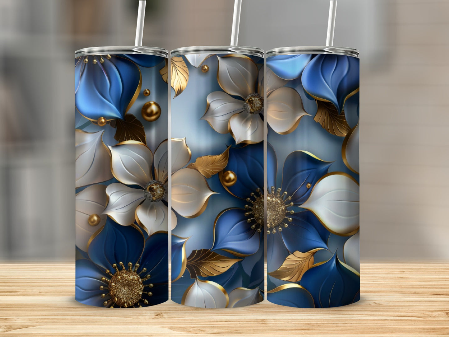 Three tumblers featuring blue and gold floral designs on a wooden surface.