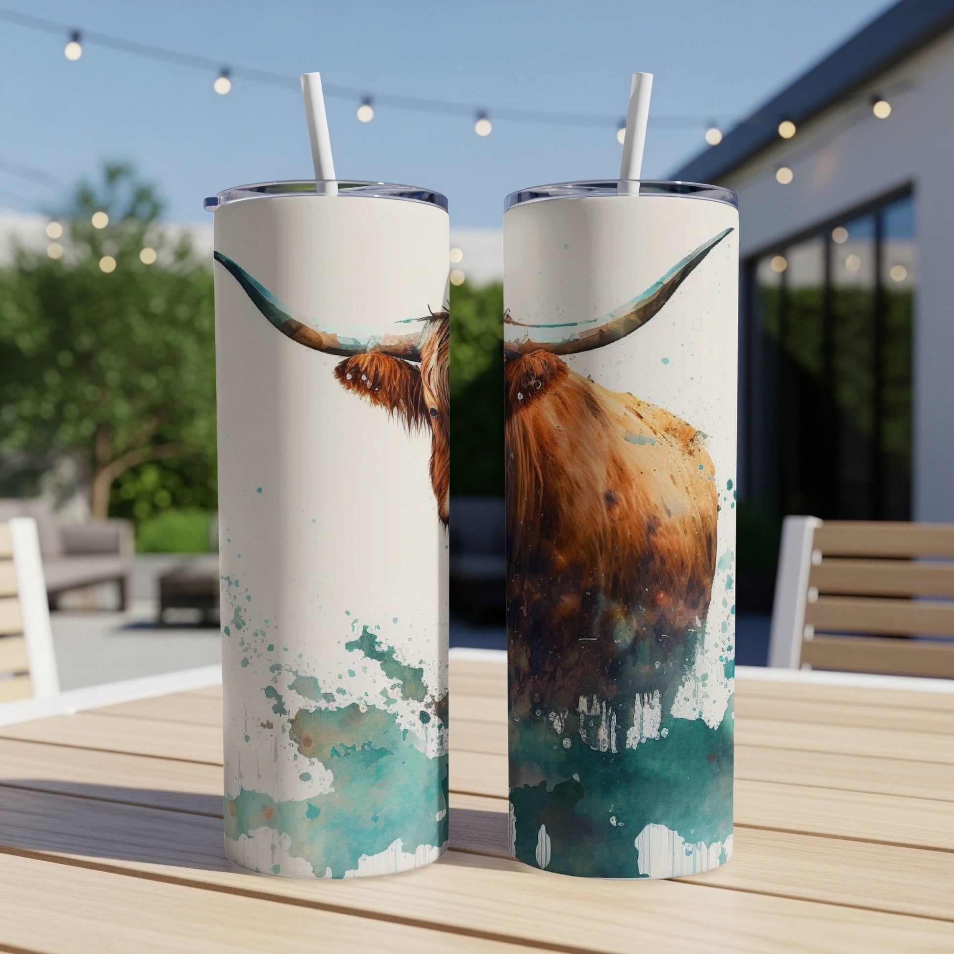 Highland cow watercolor art on two white tumblers outdoors.