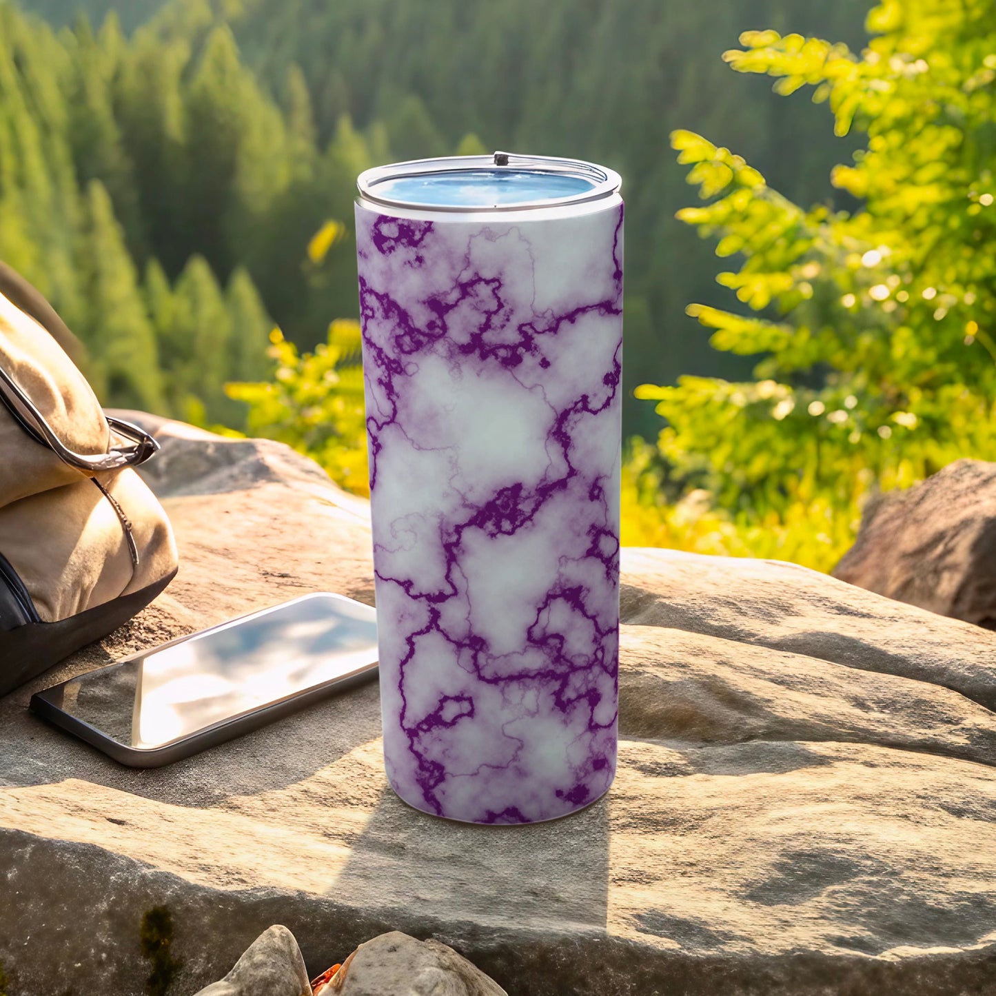Purple marble patterned tumbler with phone and bag outdoors.