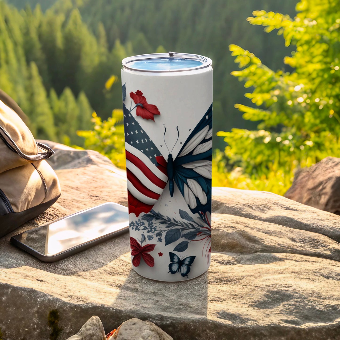 Tumbler with American flag and butterfly design on a rock.