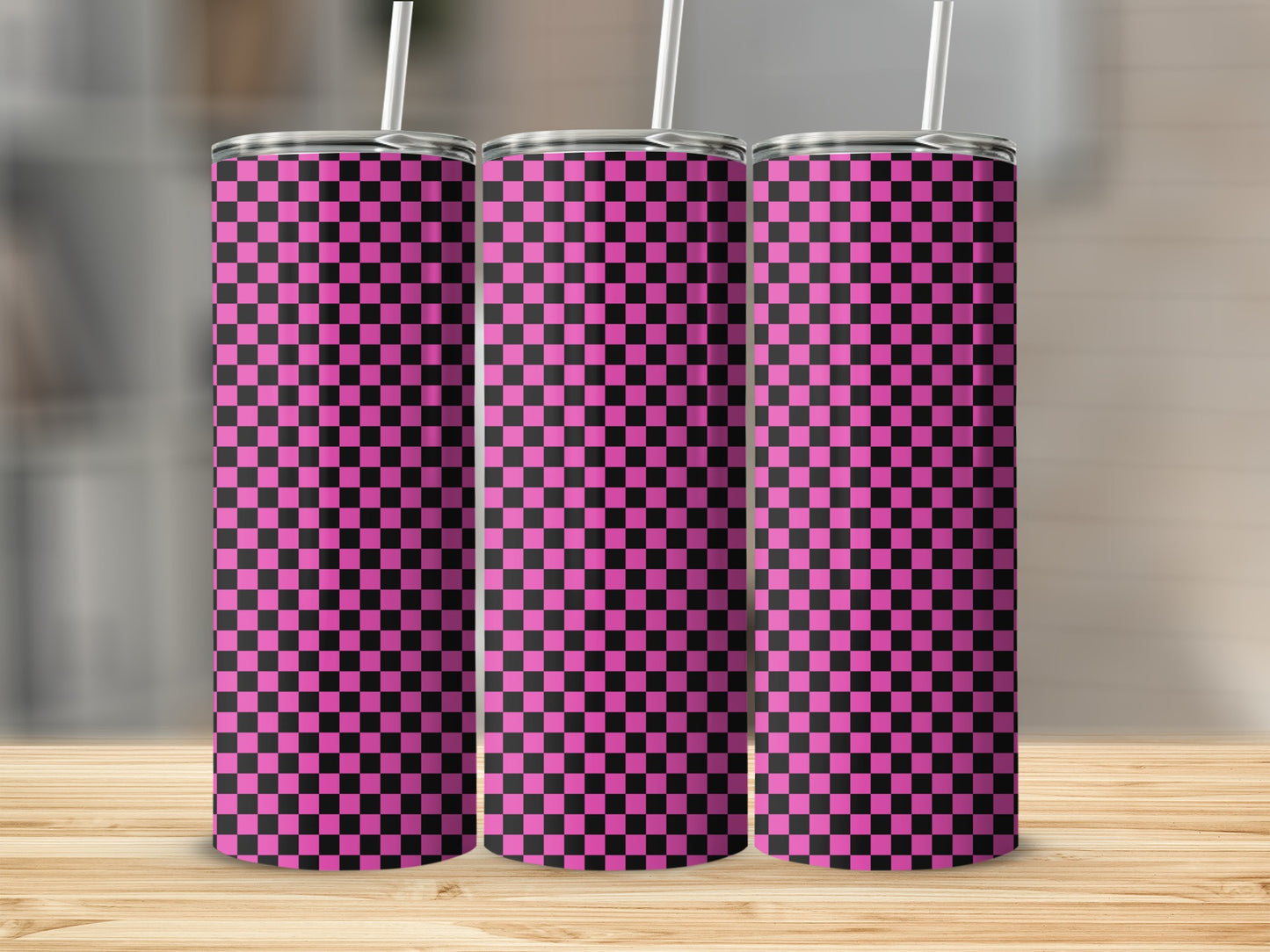 Three pink and black checkered tumblers with straws on a wooden surface.