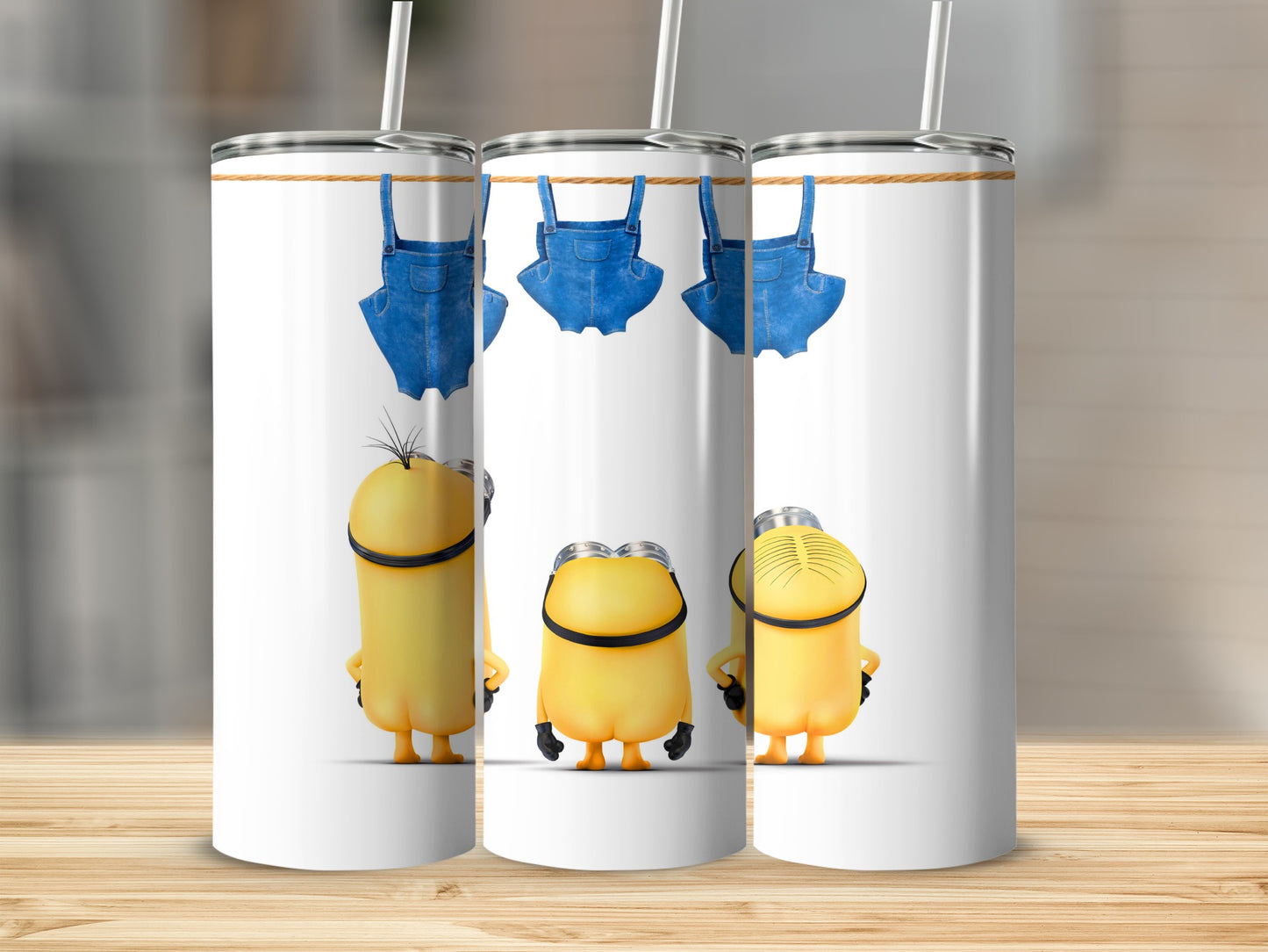 Three Minions with denim overalls hanging from a clothesline.