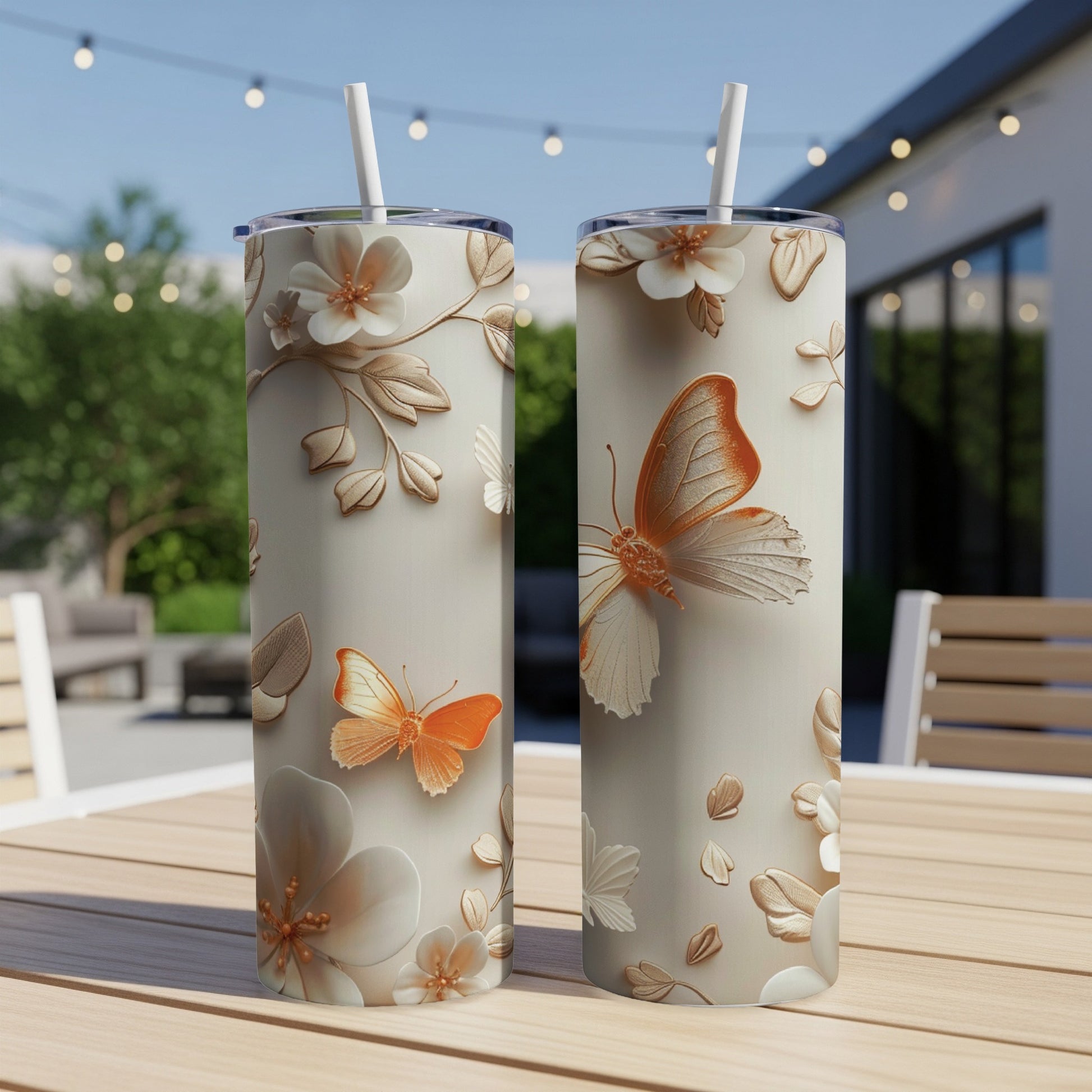 Two tall, patterned tumblers with butterflies and floral designs on a table.
