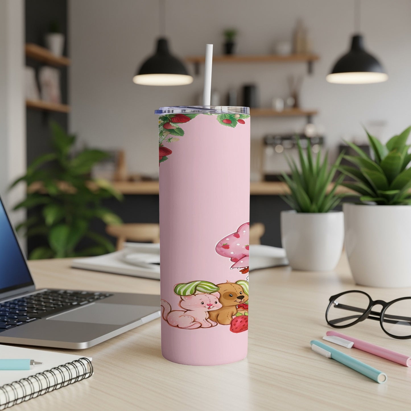 Pink tumbler with strawberry, cat, dog, and mushroom design on desk.