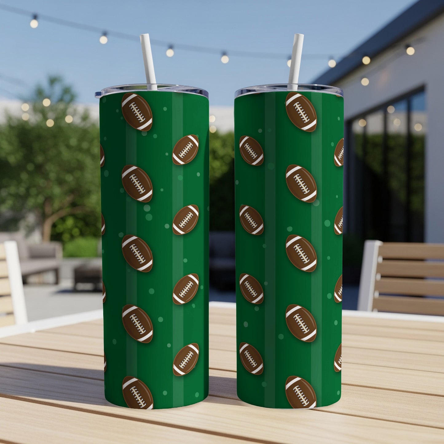 Two green tumblers with a pattern of brown footballs on a tabletop outdoors.
