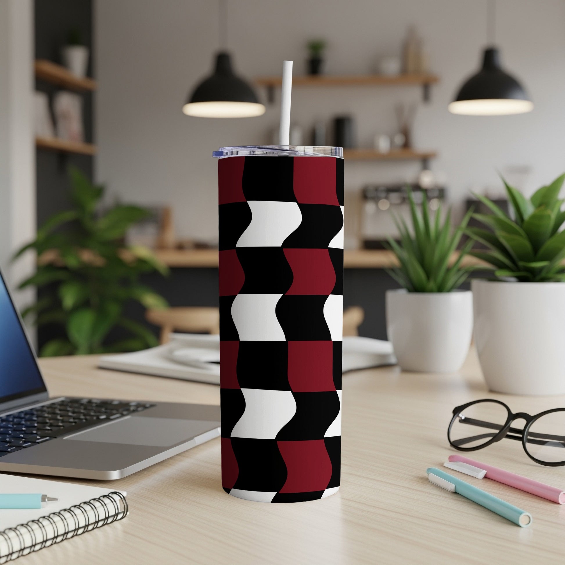 Maroon, black, and white wavy geometric pattern tumbler with straw on desk.
