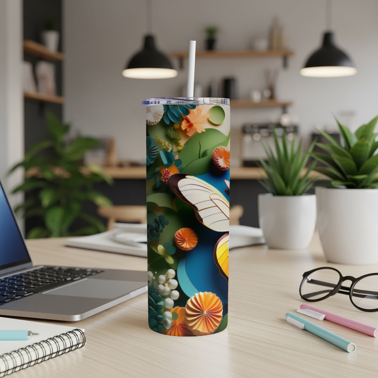 Butterfly and floral patterned insulated tumbler on a desk.