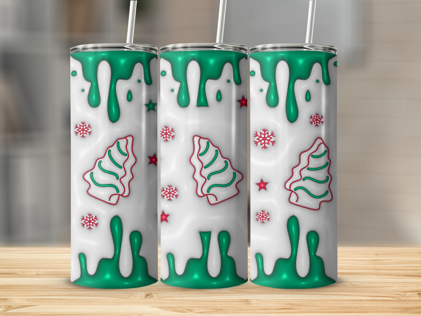 Three festive tumblers with green Christmas tree and snowflake designs on white drip pattern.