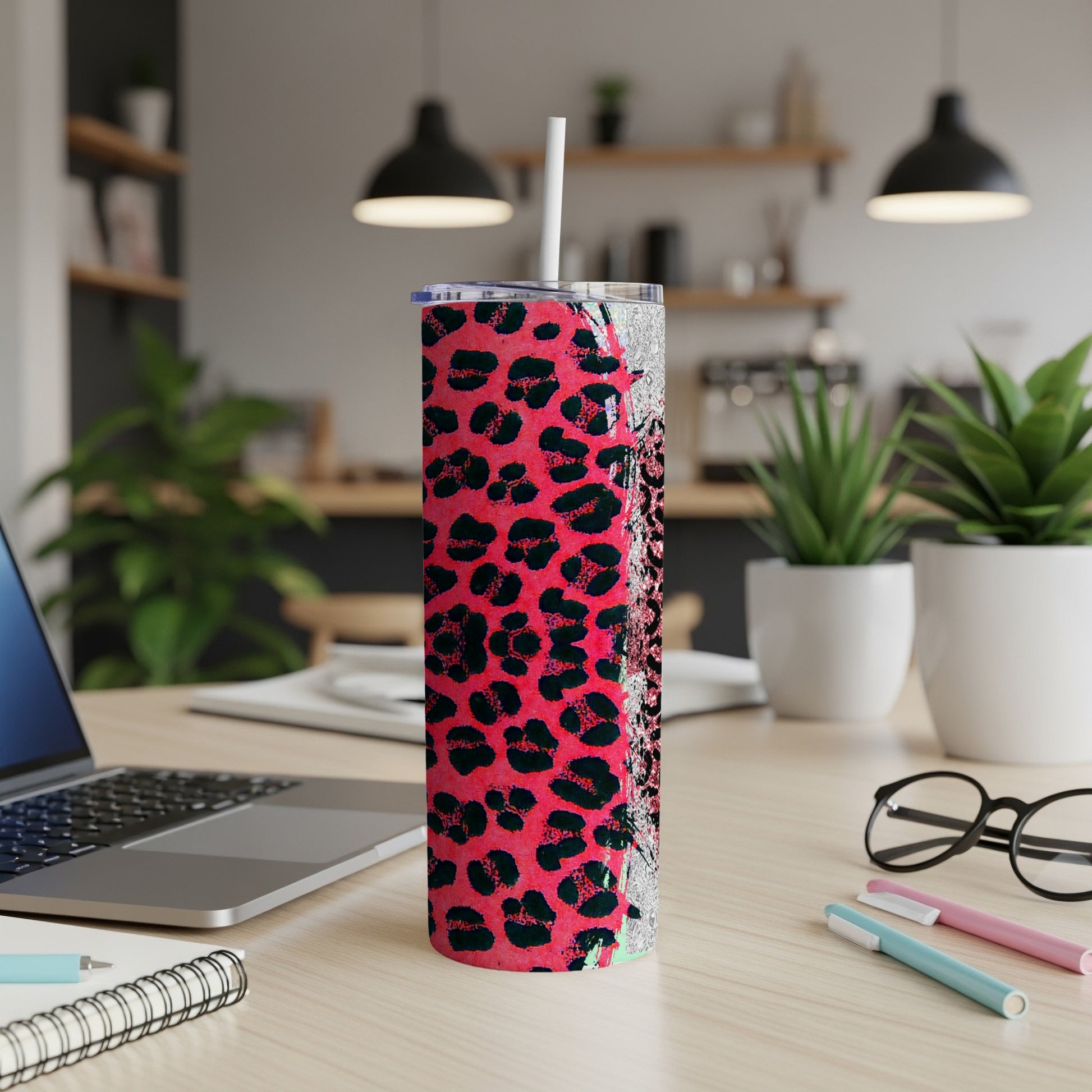 Pink leopard print tumbler with a straw on a desk.