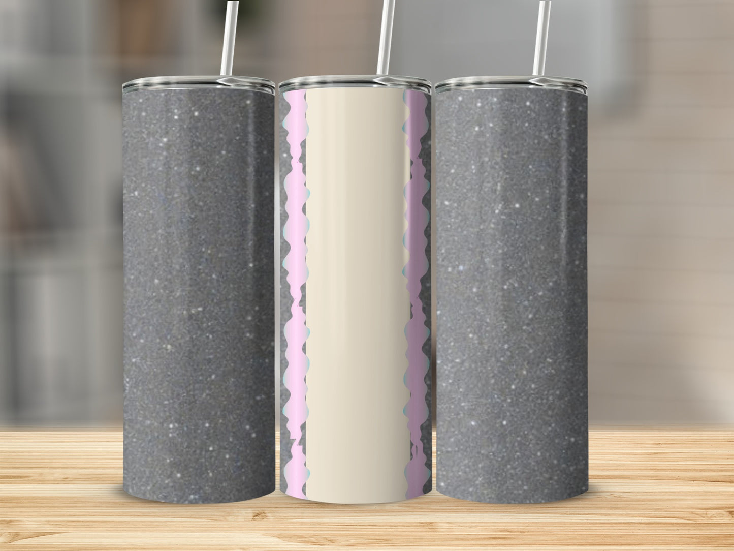 Three tumblers with glitter and a light-colored design on a wooden surface.