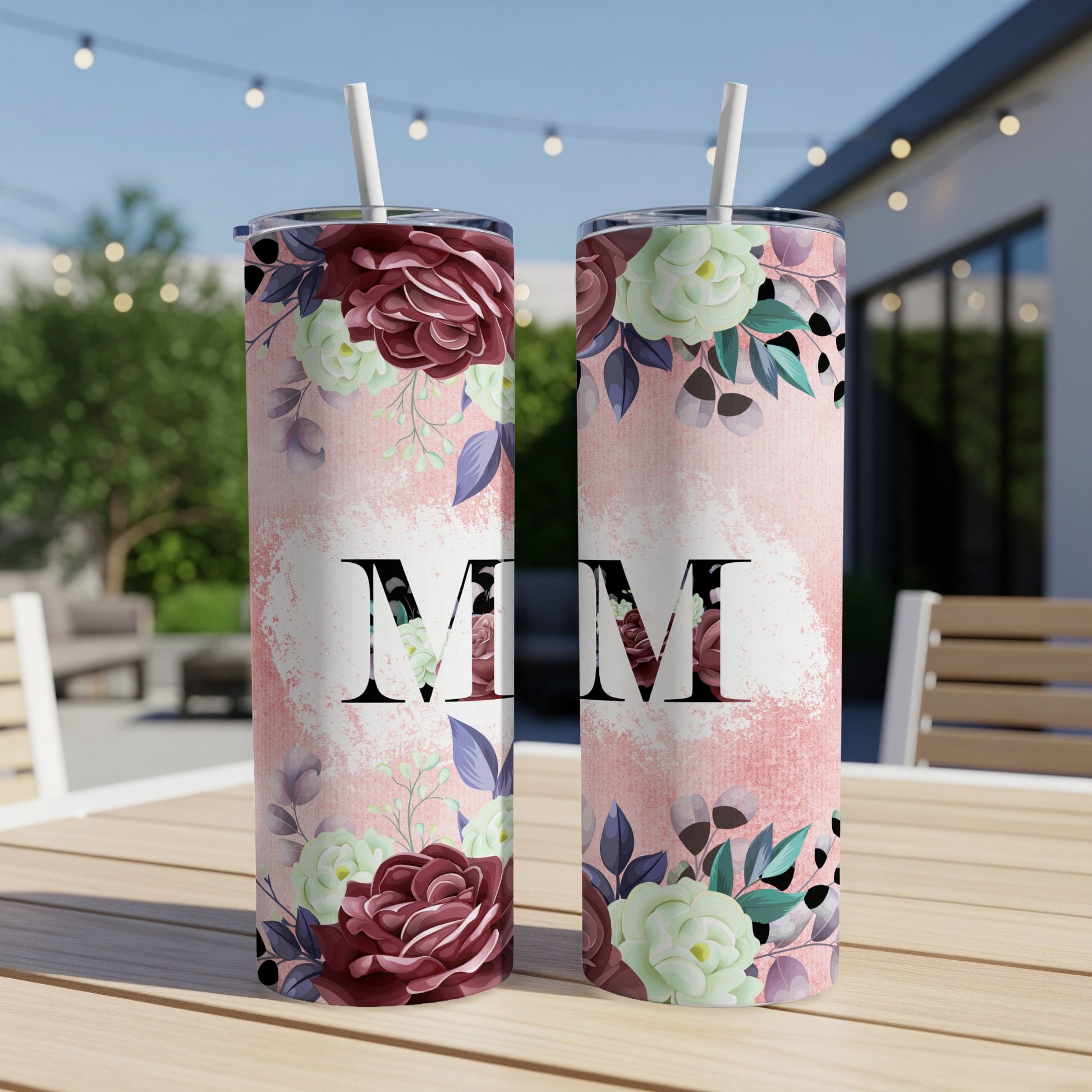 Two tumblers with floral design and "MM" initials on a wooden table.
