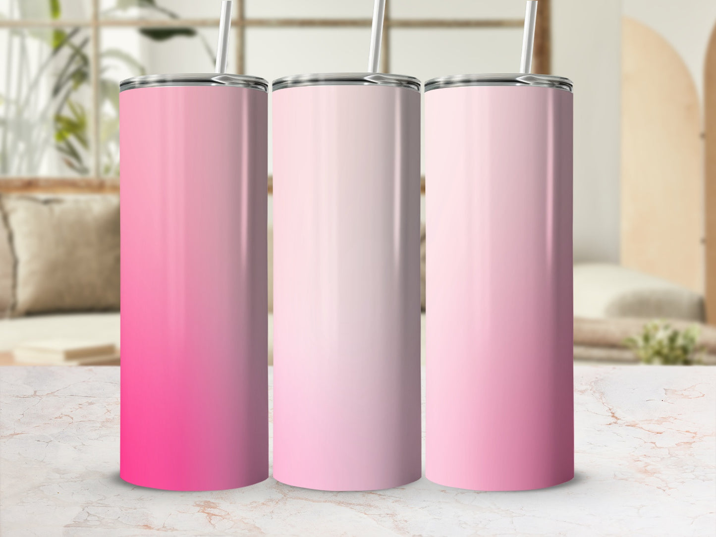 Three gradient pink tumblers with straws on a marble surface.