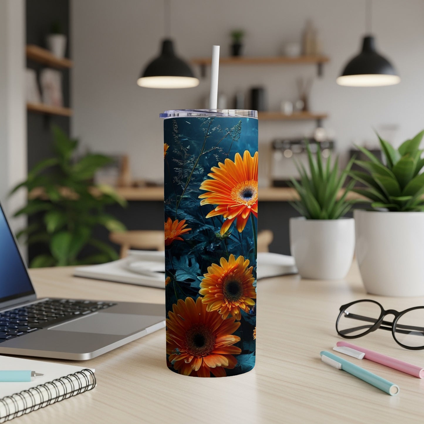 Orange gerbera daisies with green leaves on a dark background on a tumbler.