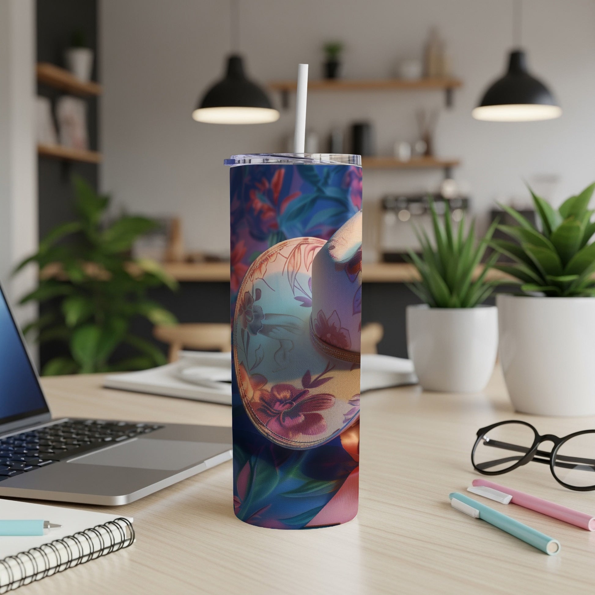 Tumbler with floral and geometric pattern, straw, laptop, and notebooks.