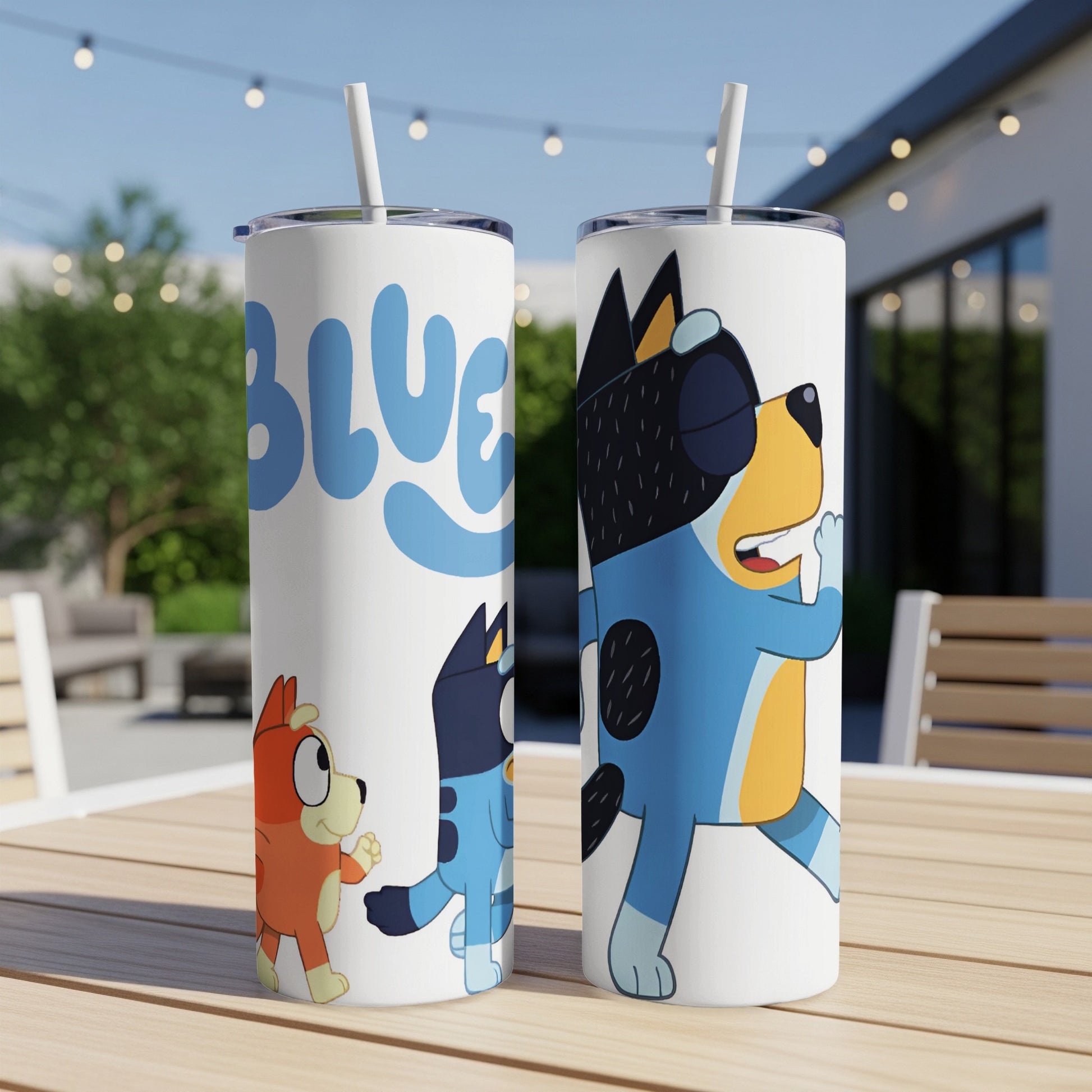 Bluey and Bingo characters on white tumblers with straws, outdoors.