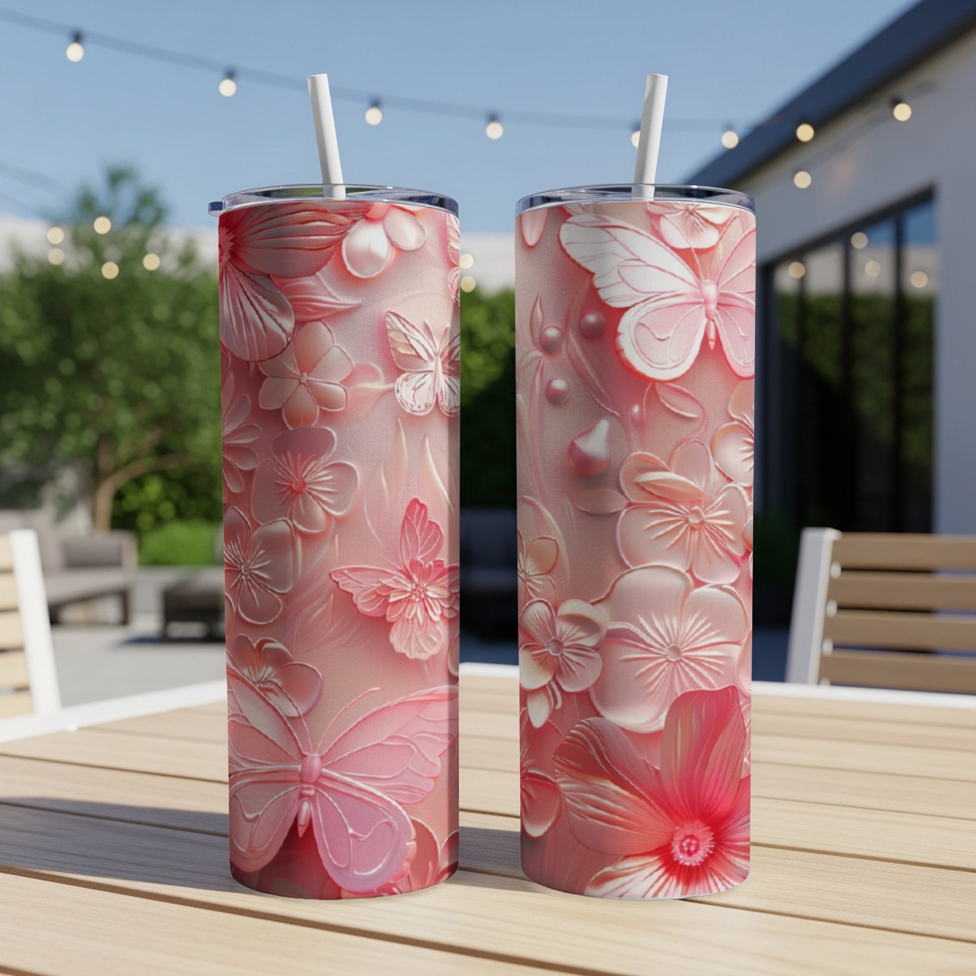 Two pink floral and butterfly patterned tumblers on a wooden table.