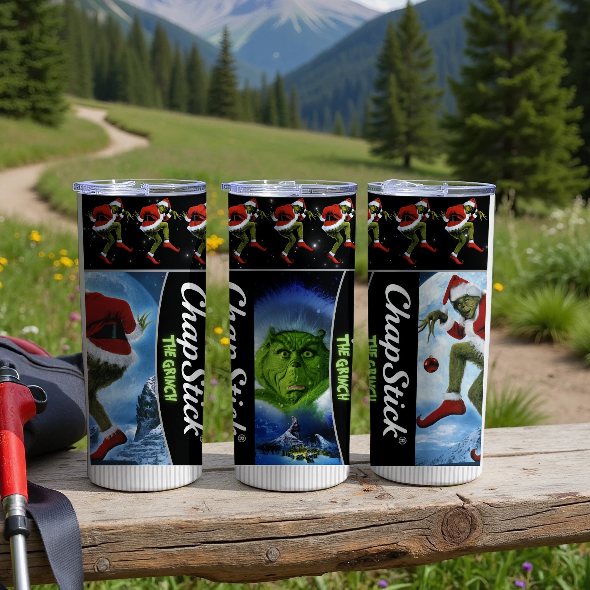 Three Grinch-themed tumblers with a mountain scene background.
