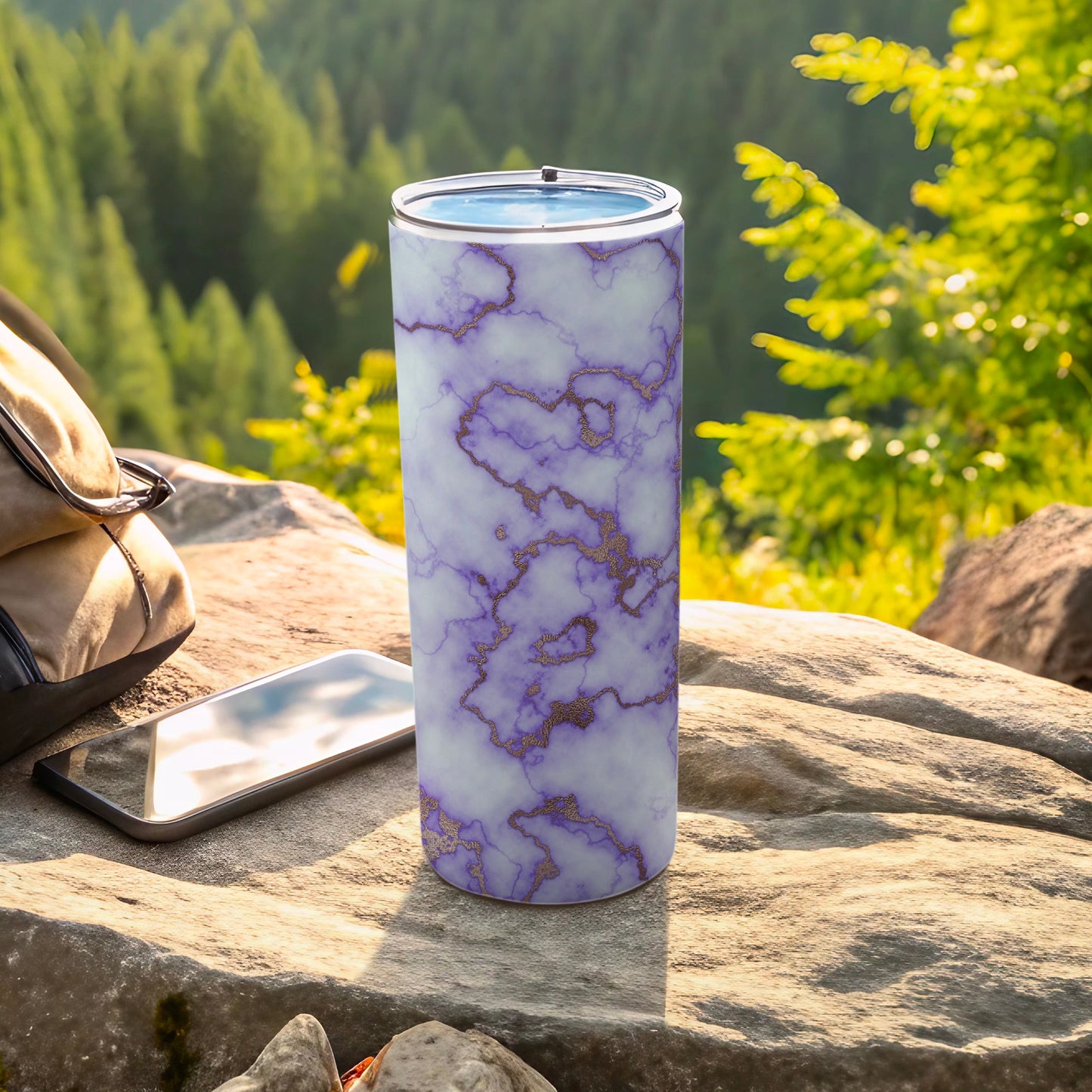 Purple marble tumbler with gold accents on a rock outdoors.