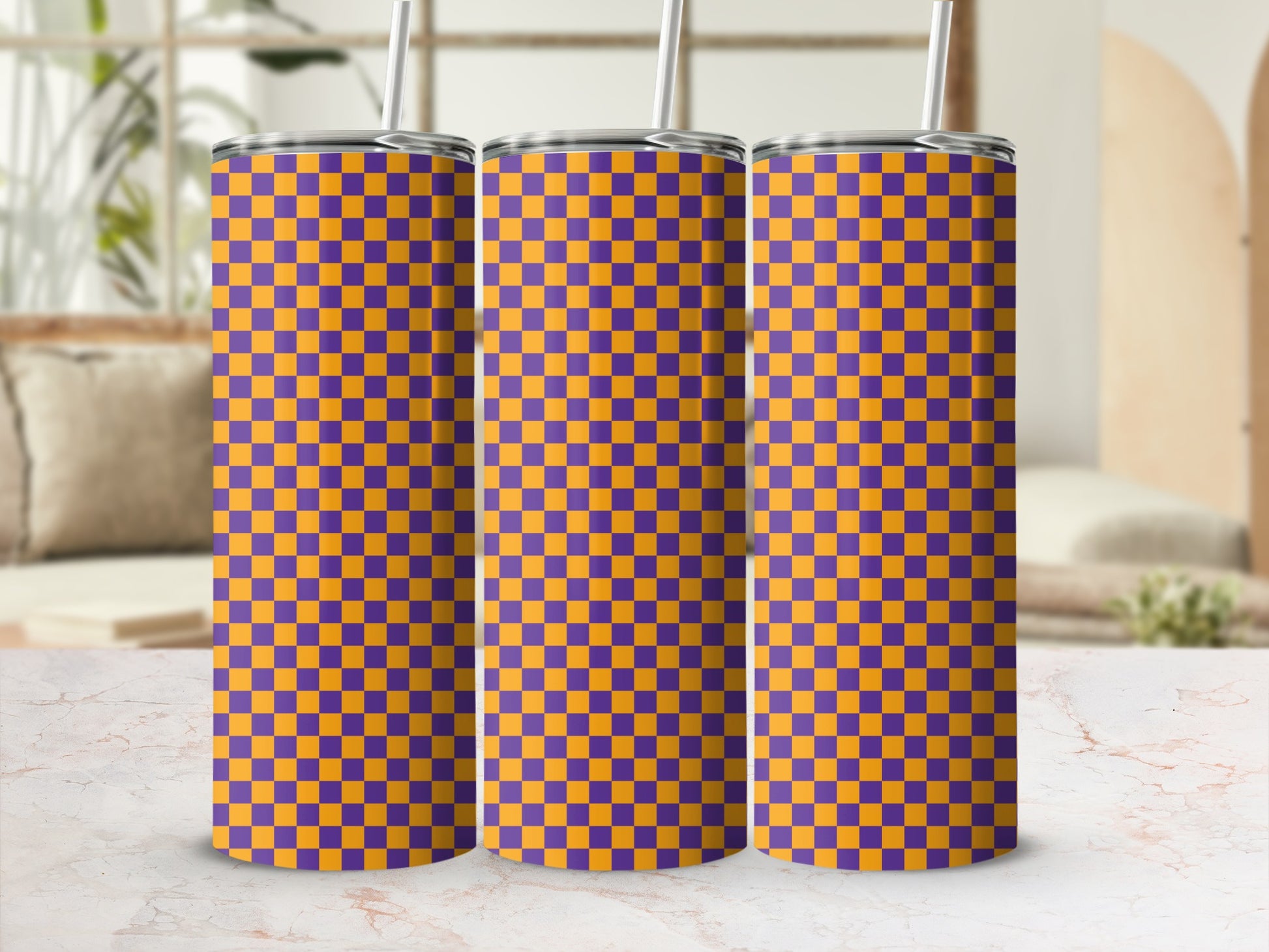 Three purple and orange checkered tumblers with straws on a marbled surface.