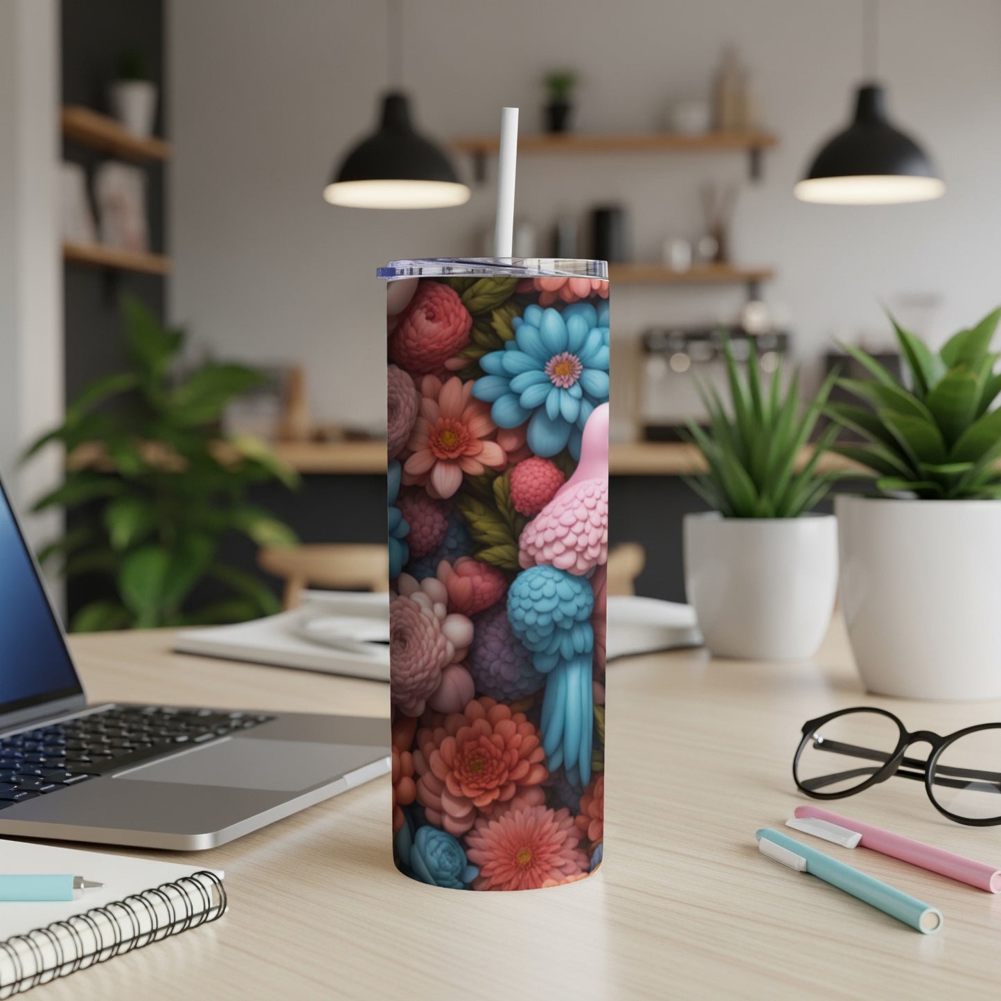 Floral parrot design on a white tumbler with a straw, on a desk.