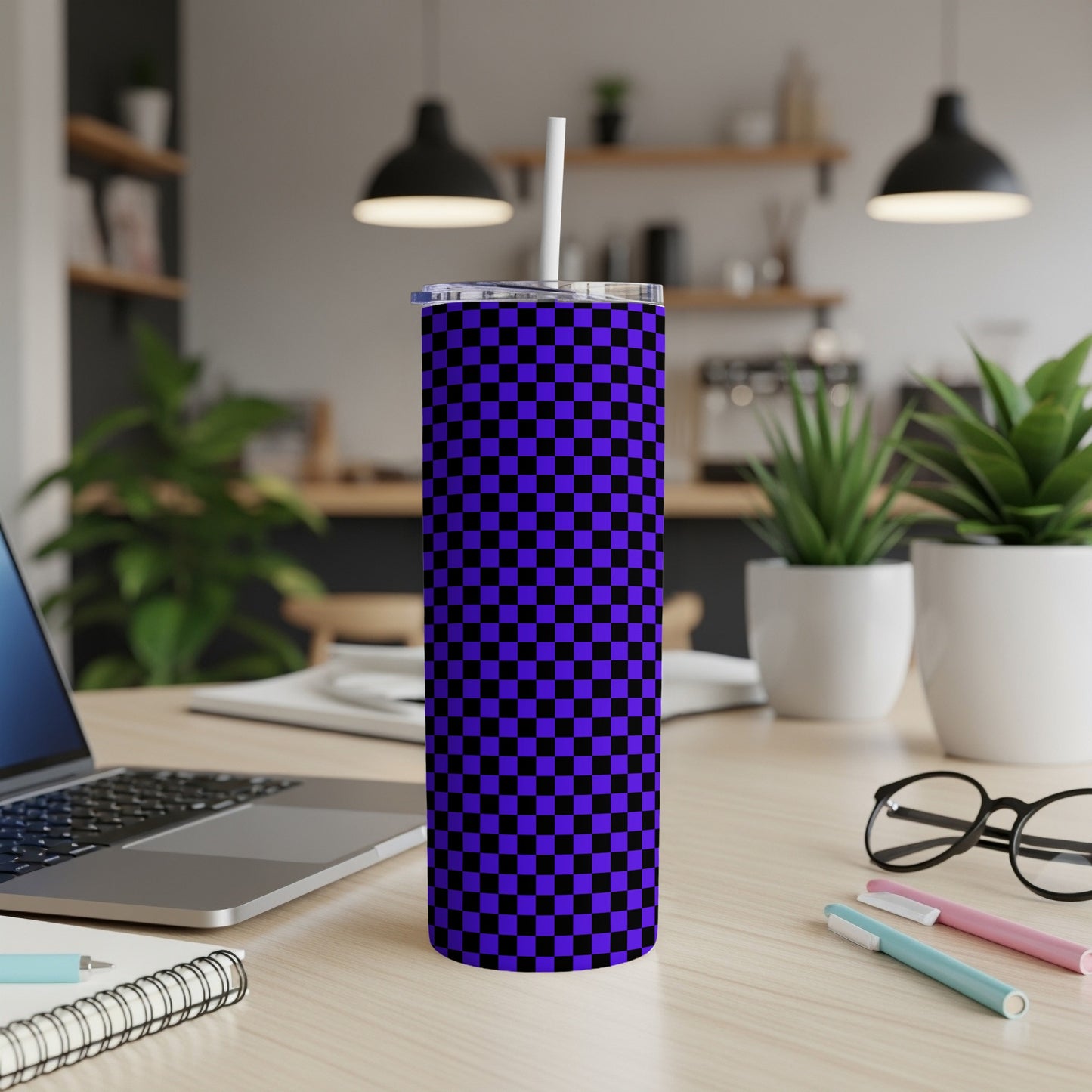 Blue and purple checkered tumbler with straw on a wooden desk.