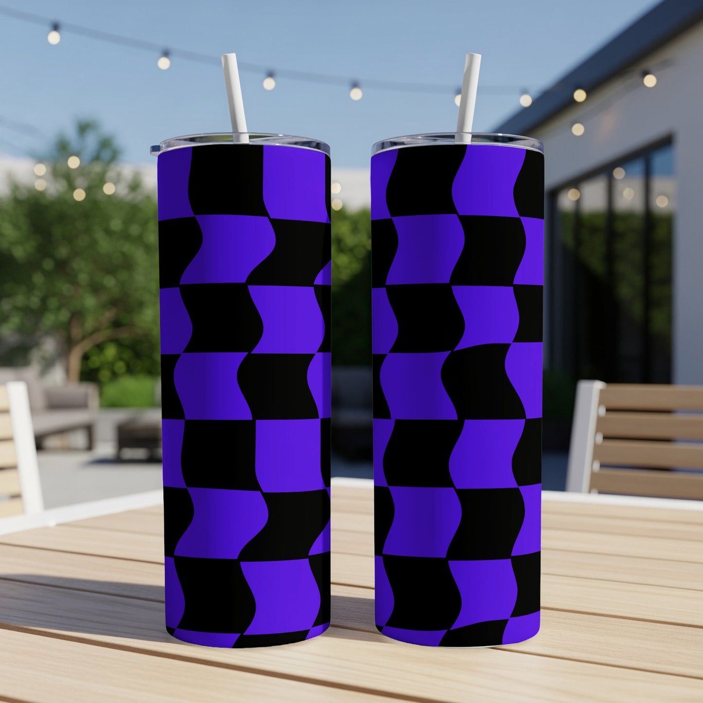 Two purple and black checkered tumblers with straws on a wooden table.