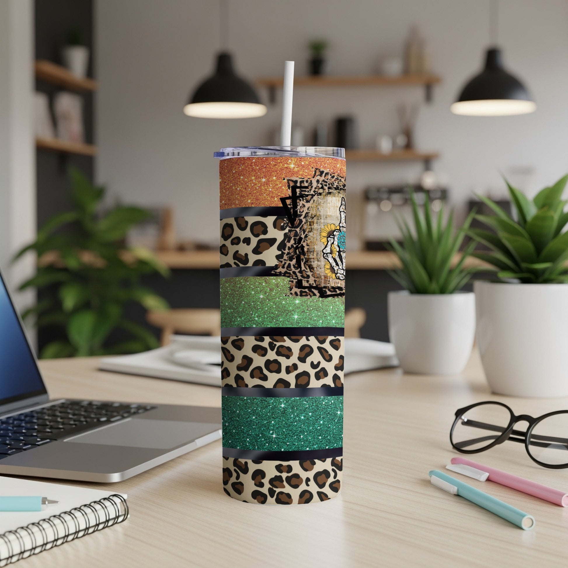 Glitter and leopard print tumbler with skull design on a desk.
