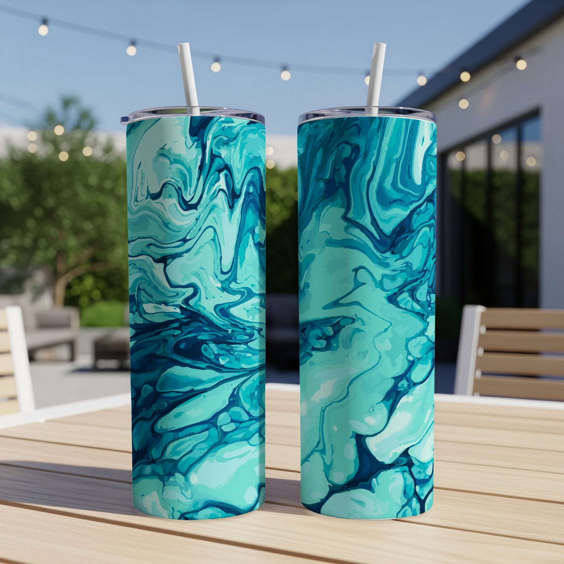 Two tumblers with teal and blue marbled pattern, each with a white straw, outdoors.