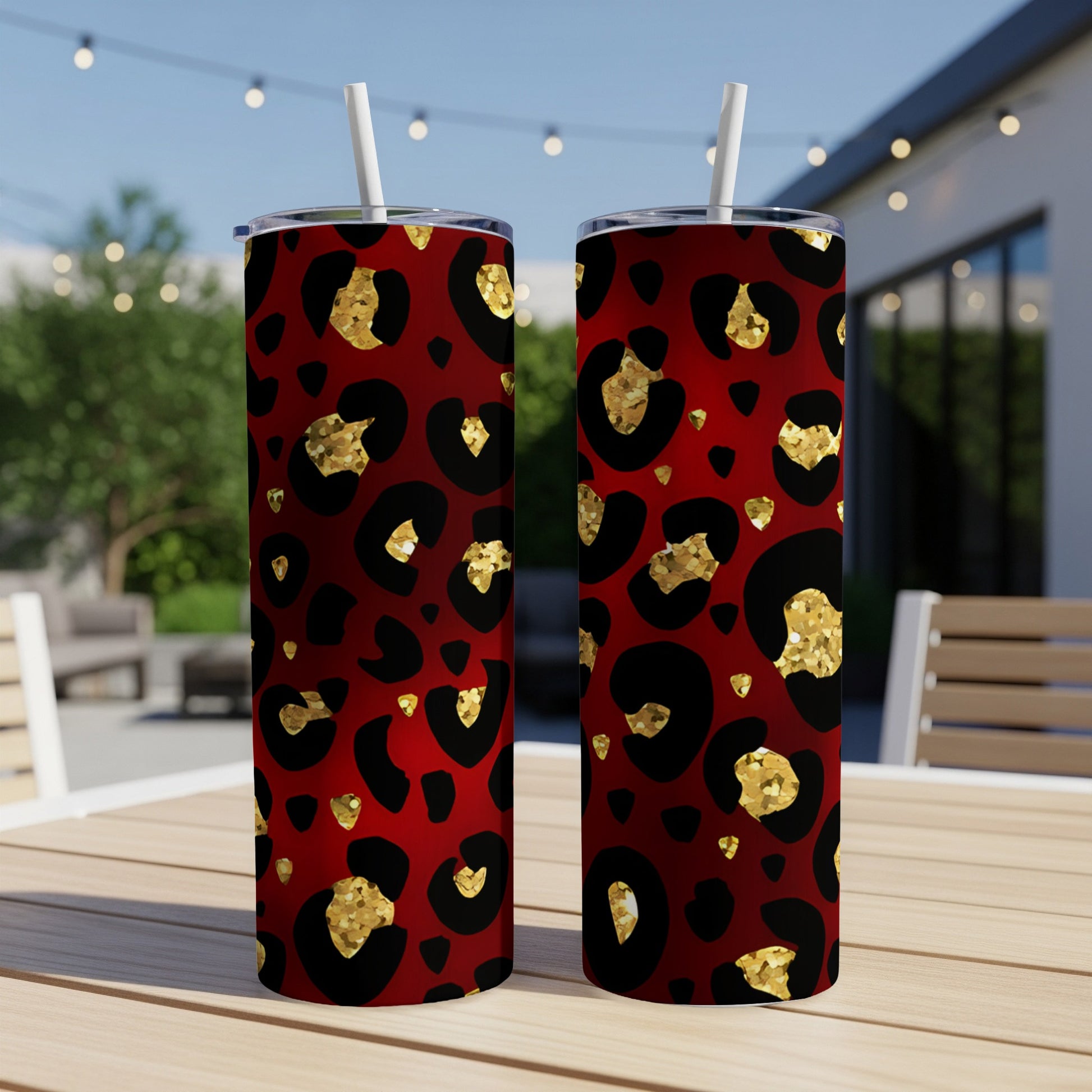Two red tumblers with gold leopard print pattern and straws.