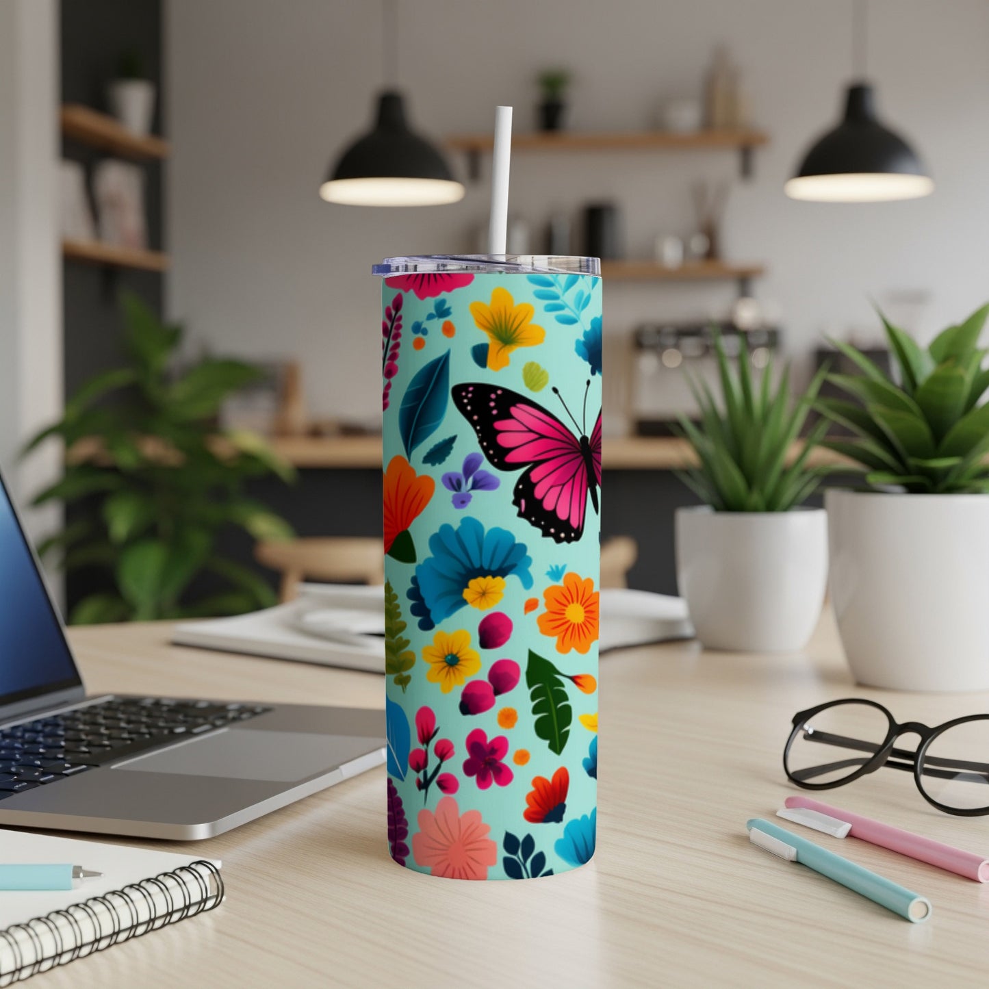 Turquoise tumbler with colorful floral and butterfly pattern, straw inserted.