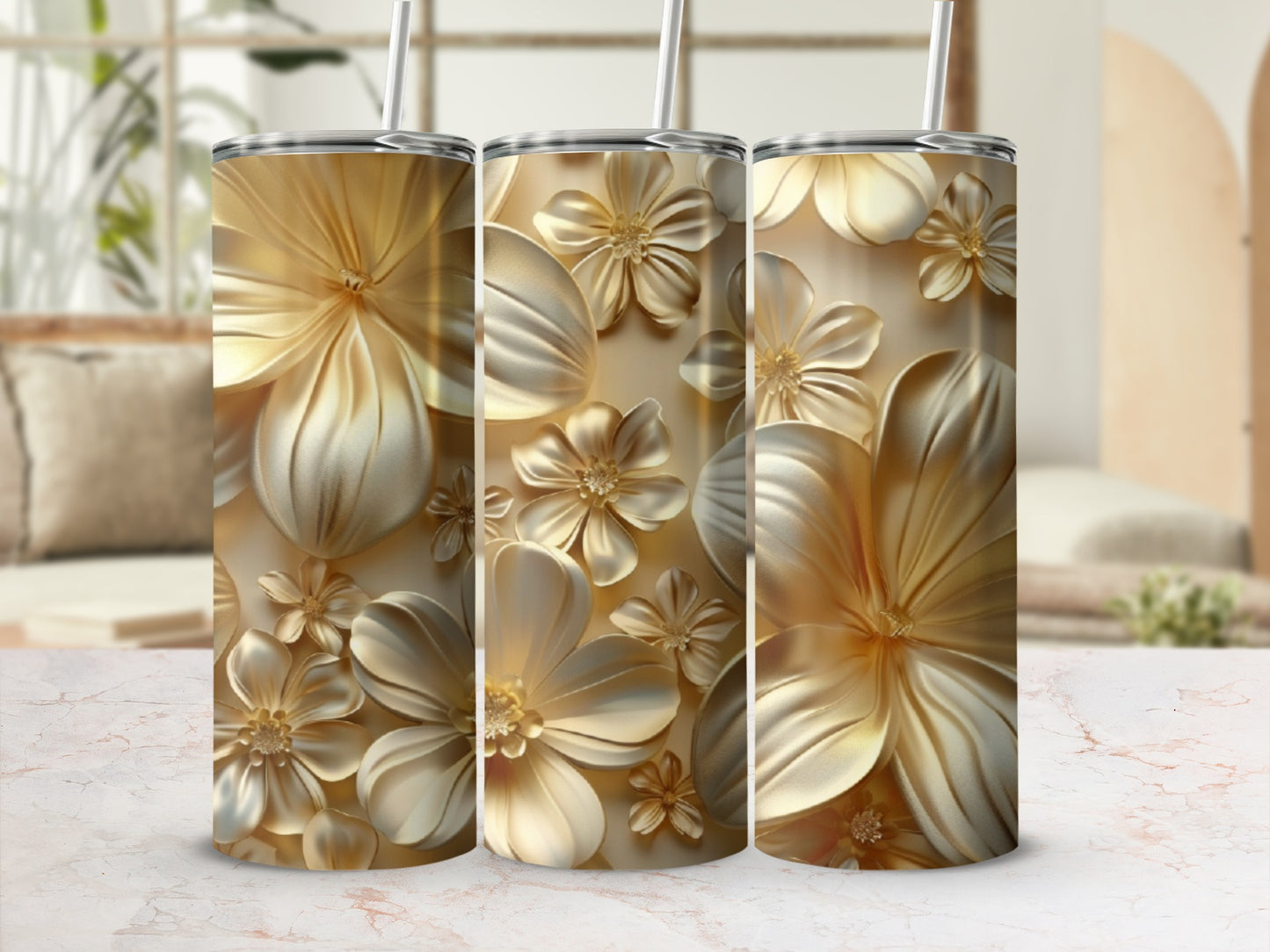 Three gold tumblers with embossed floral designs in a light background.
