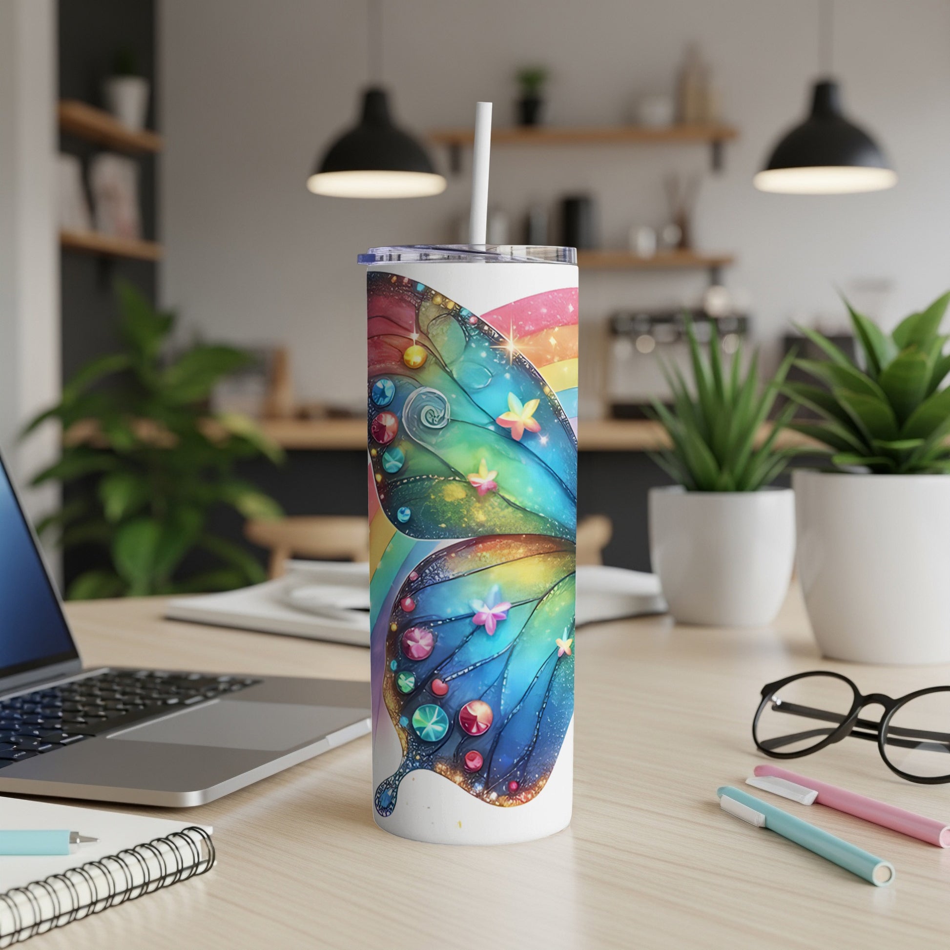 Butterfly tumbler with rainbow accents on a desk with a laptop and pens.